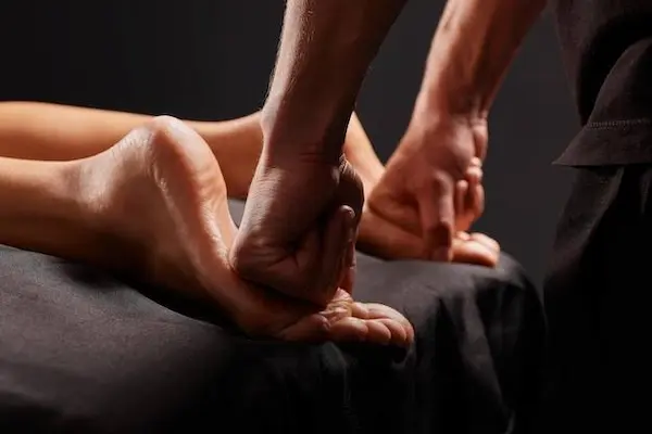 Male therapist performing foot massage for pain and stress relief at home in Varanasi
